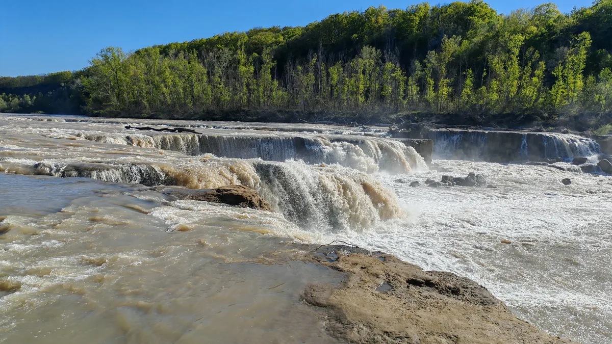 Уступы порога на Белой: мутная вода падает в белую пену.